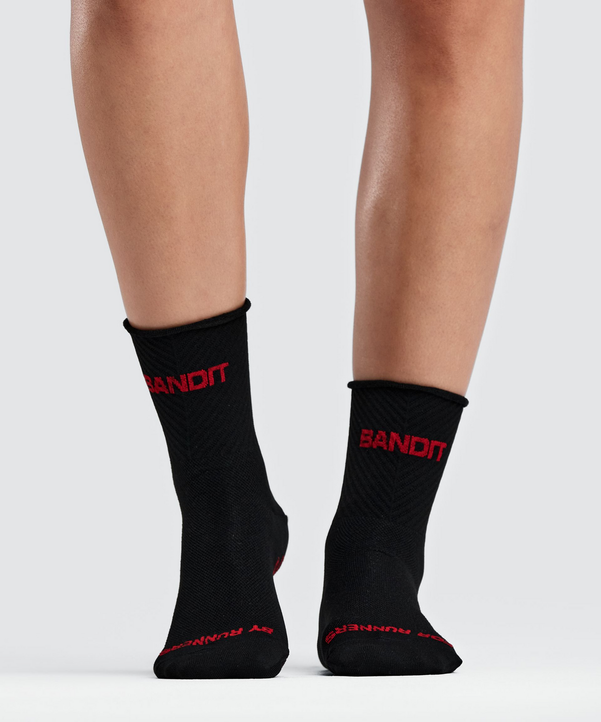 Medias de running Bandit Lite Run Ribbed, color negro con Oxide Red - vista lateral en modelo