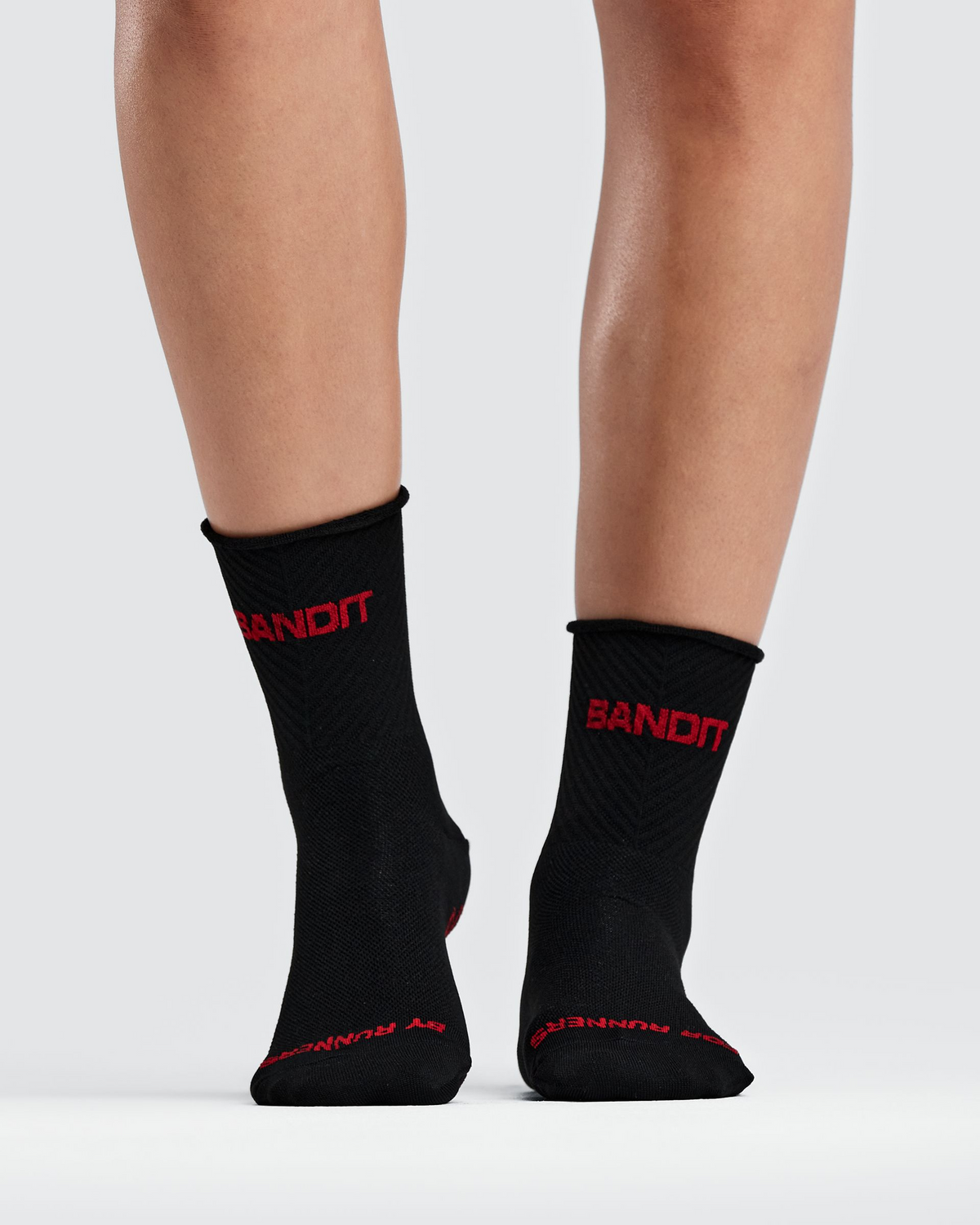 Medias de running Bandit Lite Run Ribbed, color negro con Oxide Red - vista frontal en modelo